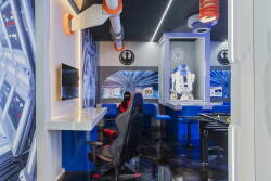 Welcome to a vibrant gaming oasis where sci-fi meets comfort, complete with sleek blue walls and glowing accents. Relax in plush seating or dive into your favorite games at our stylish high-tech workstation. Enjoy your playtime!
