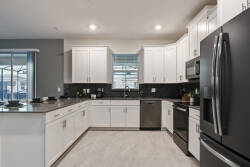 This contemporary kitchen boasts sleek white cabinets and dark granite countertops, creating a beautiful contrast. With natural light illuminating modern appliances and a spacious layout, it's perfect for your culinary adventures.