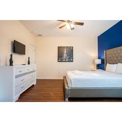 This stylish bedroom boasts a sleek gray bed with crisp white linens, a chic deep blue accent wall, and warm wood flooring, all bathed in natural light, creating a sophisticated and inviting atmosphere for your stay.