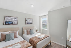 Rest in a bright bedroom with two cozy beds, soft pillows, warm blankets, abstract wall art, natural light, and clean neutral tones, creating a comfortable space for your vacation.