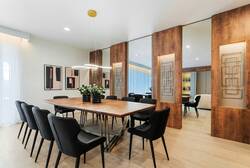 Share meals in a stylish dining area with a long wood table, black chairs, modern pendant lighting, mirrored wall accents, and easy access to the kitchen, creating a warm space for vacation gatherings.