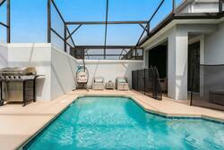 Relax in a private screened pool area with sparkling water, outdoor seating, hanging chair, BBQ grill, and open sky views, perfect for swimming and family moments during vacation.