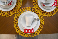 Savor delightful meals at a beautifully arranged table with vibrant yellow placemats and warm wood, complete with polished white dishware and charming red polka-dot napkins, perfect for cozy gatherings.
