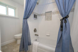 Experience a bright bathroom with soft sky-blue curtains framing a clean tub and stylish tile accents. The natural light streaming in creates a refreshing atmosphere, making your daily routines feel revitalizing and uplifting.