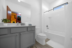 This bright bathroom features a stylish gray vanity and a clean white tub, offering a refreshing start to your day. The touch of greenery adds warmth, creating a welcoming atmosphere for your stay.
