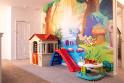 Let kids enjoy a colorful play area with a fun wall mural, playhouse, small slide, and activity table. Soft carpet, bright colors, and cheerful details create a safe and playful space for little guests.