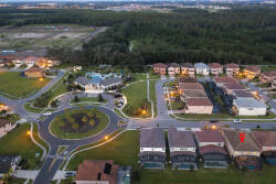 Bask in tranquil surroundings with this expansive aerial view showcasing the well-maintained community layout, neatly lined homes, and inviting green spaces. The warm evening glow adds a touch of charm, inviting you to explore.