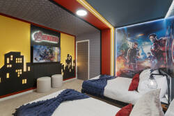 Rest in a bold superhero themed bedroom with two comfortable beds, vibrant wall art, red accents, and fun lighting. The dramatic decor creates an exciting space for kids and fans to enjoy during their vacation.