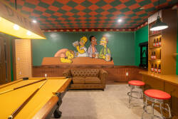 Experience a lively game room with a classic pool table and a cozy couch, perfect for unwinding. A playful mural and checkered ceiling create an inviting atmosphere, enhancing your stay and encouraging fun moments between games.