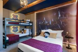 This playful bedroom offers a cozy queen bed with a rich purple throw and a stylish bunk bed for extra guests. A vibrant mural adds whimsy, while warm wood beams and soft lighting create an inviting ambiance for a delightful stay.