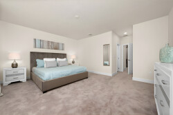 Enjoy a bright and airy bedroom featuring soft beige carpeting, a plush king-size bed with crisp turquoise linens, modern nightstands, and a sleek dresser, all enhanced by a welcoming mirror for a stylish and comfortable stay.