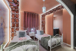Step into a charming princess themed bedroom with two cozy beds, soft pink curtains, floral accents, butterfly details, and a magical castle mural. The gentle lighting and sweet decor create a dreamy space for kids to relax during vacation.