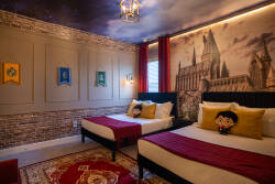 Enter a whimsical bedroom with rich red accents and playful decor that ignites your imagination. A textured brick wall adds charm to two cozy beds, while warm lighting creates a soothing glow, inviting you to relax and unwind.