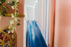 Experience a playful escape with this vibrant blue slide, seamlessly integrated into the colorful decor. Soft natural light filters through the large windows, highlighting the whimsical design elements and inviting a sense of fun.