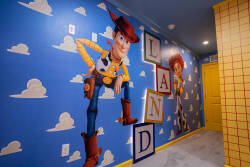 Welcome to a vibrant playroom filled with colorful murals of beloved characters. Bright blue walls with fluffy clouds spark creativity, while a playful yellow door adds a cheerful touch to this whimsical atmosphere.
