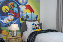 This playful bedroom bursts with bright colors and a vibrant mural of beloved characters. Cozy beds with plush throws create a charming atmosphere, perfect for unwinding after a day full of adventure and fun.