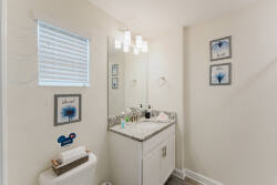 Enjoy a bright, airy bathroom with a sleek white vanity and striking gray speckled countertop. Charming fixtures and cheerful wall art enhance the space, while natural light creates a fresh ambiance for a truly relaxing.