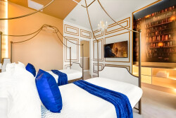 This stylish bedroom features a vibrant mix of gold accents and rich blue textiles, creating a cozy atmosphere. The elegant canopy bed and modern bookshelf backdrop invite relaxation for restful nights.