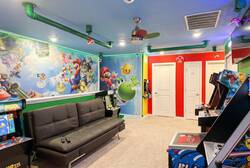 Enjoy a fun Super Mario themed game room with arcade machines, colorful wall art, a cozy sofa, bright lighting, and playful decor, perfect for family entertainment during vacation.