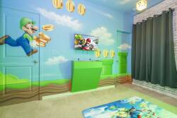 Step into a playful world with vibrant mural art featuring beloved characters, complemented by a cozy carpet and a sleek, green console. The room is well-lit, creating an energizing atmosphere perfect for relaxation and fun.
