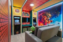 Step into this vibrant game room, adorned with bold colors and eye-catching graphics that celebrate classic gaming. The plush gray sofa invites you to unwind while the arcade machines promise hours of entertainment for all ages.