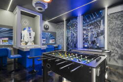 Step into a vibrant game room featuring a sleek foosball table and striking blue accents that energize the atmosphere. The playful decor includes iconic sci-fi elements, ensuring endless fun for guests of all ages.