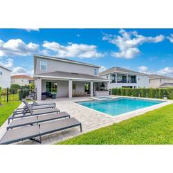 Relax in a spacious backyard with a private pool, raised spa, lounge chairs, covered patio, outdoor kitchen, and dining area, perfect for sunny Florida days with family.