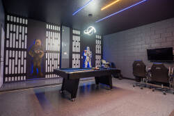 Experience a uniquely themed game room with a sleek pool table and vibrant neon lights for a playful vibe. Enjoy striking wall art and comfortable seating that invites both friendly competition and relaxation.