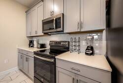 Experience our stylish kitchen with modern appliances and sleek gray cabinetry, ideal for whipping up your favorite meals. The bright countertops and spacious layout create a functional and inviting space for your culinary.