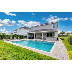 Relax in a spacious backyard with a private pool, raised spa, lounge chairs, covered patio, outdoor kitchen, and dining area, perfect for sunny Florida days with family.