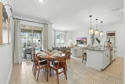 Enjoy a spacious dining area featuring a beautifully set wooden table and stylish pendant lighting. This bright space seamlessly connects to a modern kitchen, creating a warm atmosphere perfect for meals and gatherings.