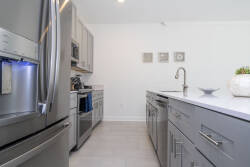 This stylish kitchen boasts stainless steel appliances and a minimalist design with soft gray cabinetry and an open layout, offering a clean, modern space ideal for your culinary adventures.