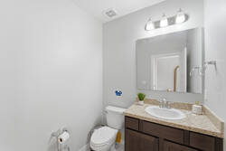 Refresh in a bright half bathroom with a granite vanity, large mirror, soft lighting, neutral tones, and clean finishes, offering a simple and comfortable space for your vacation.