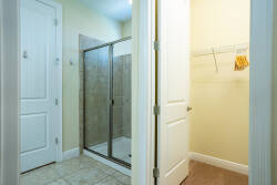 Experience a bright bathroom with a sleek glass shower and cozy tile flooring. The neutral walls enhance the spacious layout, and the organized closet provides convenient storage for all your belongings. Enjoy your stay!