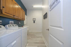 Discover a beautifully designed laundry area with elegant wooden cabinetry and modern appliances for your convenience. The soothing teal accent wall adds a refreshing touch, making this space both functional and inviting for you.