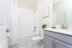 Enjoy a clean, functional bathroom with a sleek gray vanity and a bright mirror that fills the space with natural light. The crisp white shower curtain and tiled floor provide a refreshing atmosphere for your stay.