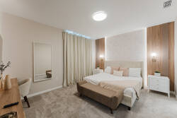Enjoy restful nights in our beautifully designed bedroom, where soft beige tones and plush carpeting invite relaxation. The stylish headboard and ambient lighting create a cozy atmosphere, complemented by a large mirror that.