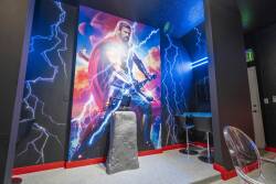 Enjoy a lively atmosphere with a stunning superhero mural and vibrant blue and red lighting. The stylish bar stools and unique stone pedestal set the stage for casual gatherings, ensuring a fun and energetic vibe for everyone.