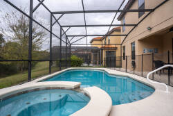 Step outside to your private oasis featuring a shimmering pool and inviting spa, all under a protective screen for added comfort. The backdrop of lush greenery creates a tranquil atmosphere, perfect for relaxation.