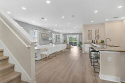 Gather in a bright open space with a modern kitchen, granite island, stainless steel appliances, dining area, soft curtains, wood flooring, and easy access to the living room.