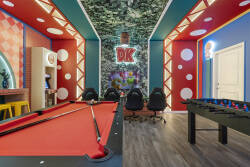 Play in a colorful Super Mario game room with a pool table, arcade machine, fun wall art, bright lighting, and bar stools, creating a lively space for family entertainment during vacation.