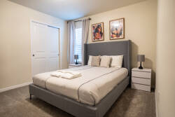 Wake up to natural light in this beautifully decorated bedroom with a plush gray bed and matching nightstands. The soft color palette and framed artwork create a cozy, relaxing atmosphere for your stay.