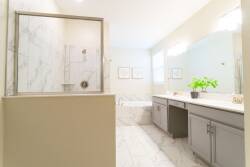 Relax in the elegant atmosphere of this beautifully designed bathroom, featuring a sleek marble shower and dual vanities. Soft lighting complements the neutral tones, with a touch of greenery for a refreshing vibe.