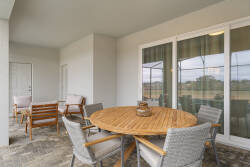 Relax on a covered patio with a round dining table, cozy outdoor seating, sliding glass doors, and peaceful green views, perfect for meals and family moments outside.