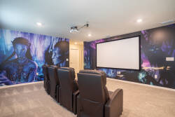 Welcome to the media room, where plush leather recliners invite you to relax. Enjoy vibrant wall art that enhances your movie nights, all while you settle in for an unforgettable experience on the large projection screen.