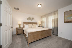 Enjoy restful nights in this cozy bedroom with a plush king-sized bed, soft beige walls, and natural light from elegant sheer curtains. Tasteful artwork and stylish nightstands create a relaxing atmosphere for your stay.