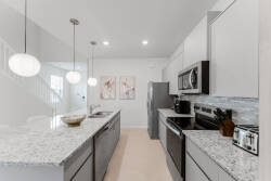 Experience a beautifully designed kitchen with sleek gray cabinetry and a stunning granite countertop that inspires culinary creativity. The warm pendant lights and modern appliances create a delightful atmosphere for cooking.