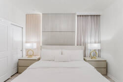 Wake up in a spacious bedroom adorned with soft, neutral tones, where natural light bathes the area. Enjoy the sleek, minimalist design featuring a plush, oversized bed and elegant bedside lamps, perfect for cozy evenings.
