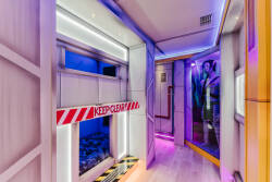 Step into a uniquely themed corridor adorned with vibrant lighting and playful decor. The sleek walls and industrial accents create an intriguing atmosphere, inviting you to explore the imaginative spaces that await beyond.