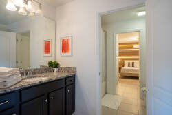 Step into this stylish bathroom where sleek dark cabinetry contrasts beautifully with the light, spacious layout. The elegant granite countertop adds a touch of sophistication, while soft lighting creates a welcoming atmosphere.